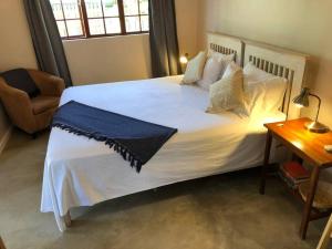 a bedroom with a large white bed and a chair at Modern Industrial Cottage in Kingsburgh