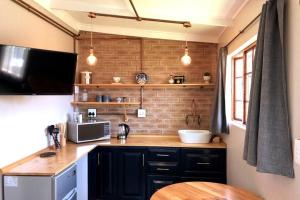 a kitchen with black cabinets and a brick wall at Modern Industrial Cottage in Kingsburgh
