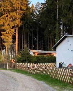 a fence and a house next to a road at Tiny House - Auszeit im Wald am Badesee in Tanna