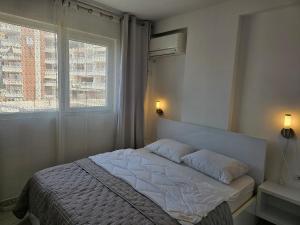 1 dormitorio con 1 cama con 2 almohadas y ventana en Vista View Sunshine apartment, en Sarandë