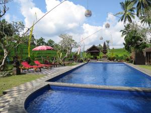 a pool at a resort with chairs and tables at Kebun Villa, Belimbing, Bali in Tabanan