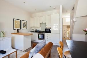 cocina y sala de estar con armarios blancos y mesa en The Kilburn Crib - Stunning 3BDR Flat, en Londres