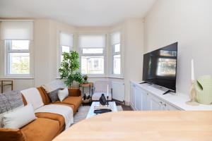 a living room with a couch and a flat screen tv at The Kilburn Crib - Stunning 3BDR Flat in London
