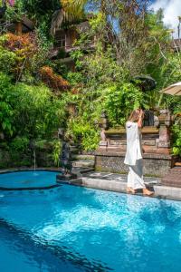 a woman standing in the water near a swimming pool at Down The Rabbit Hole in Ubud