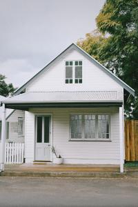 a white house with a porch and a fence at The Old Shop - Byron Region Hinterland 