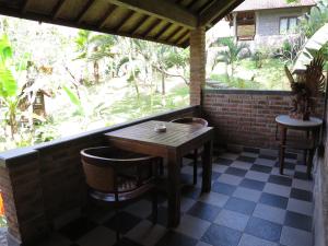 a table and chairs on a porch with a window at Kebun Villa, Belimbing, Bali in Tabanan