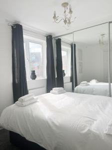 a white bedroom with two beds and a mirror at Witton House by Blue Skies Stays in Stockton-on-Tees
