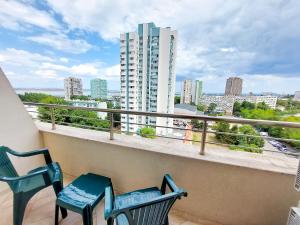 two chairs on a balcony with a view of a city at Апартаменти за гости Делукс in Burgas City