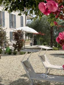 a table and chairs with an umbrella and pink flowers at Tenuta Dei Vicini - Luxury Apartments in San Marzano Oliveto