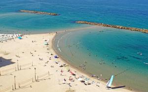 a beach with a lot of people in the water at Ben Yehuda 2 Bedrooms Apartment in Tel Aviv