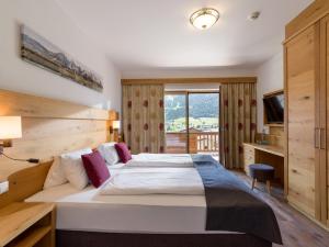 um quarto de hotel com uma cama grande e uma janela em Hotel Alpenpanorama em Söll