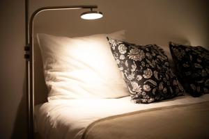 a bed with white pillows and a lamp on it at #9 3mins to station 1stop to Shinjuku Stylish apartment with plenty of sunlight in Tokyo