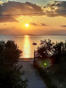 a sunset over the water with a boat in the ocean at Amalfi Complex in Kato Almiri