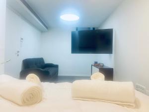 uma sala de estar com 2 cadeiras brancas e uma televisão de ecrã plano em Buchman Cozy 1Bedroom Haven em Modi'in