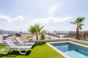 a swimming pool with two lounge chairs next to a swimming pool at Casa con piscina climatizada y vistas al mar in Polop