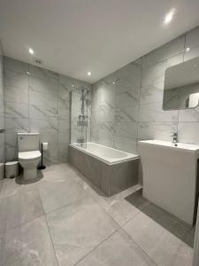 a bathroom with a tub and a toilet and a sink at Queens Apartment 1 in Blackpool