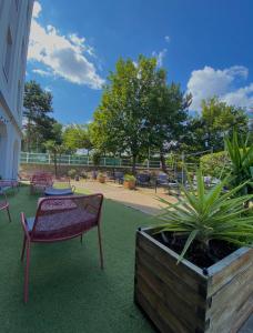 un patio avec un banc, une table et des plantes dans l'établissement Kyriad Le Blanc-Mesnil, au Blanc-Mesnil