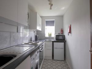 a white kitchen with a sink and a microwave at Pass the Keys Comfortable flat in Scunthorpe