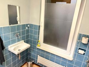 uma casa de banho em azulejos azuis com um lavatório e um espelho em Apartment in Düren em Düren - Eifel