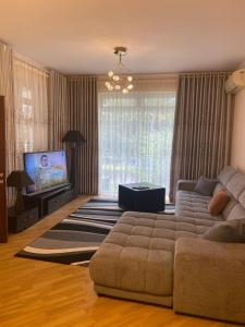 sala de estar con sofá y TV de pantalla plana en Иссык-Куль ЦО "Karven Four Seasons" таунхаус, en Chon-Sary-Oy