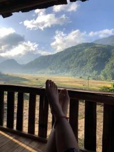 una persona sentada en un porche con vistas a las montañas en A Lử Homestay, en Mù Cang Chải