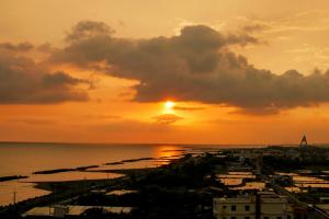 a sunset over a harbor with the sun setting at 緩慢大鵬灣 in Donggang