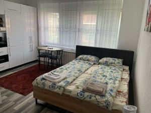 a bedroom with a bed with a table and a kitchen at Stan na dan, Pazar Tuzla - centar grada in Tuzla