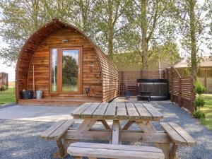 a wooden cabin with a picnic table and a grill at Mischief in Harpham