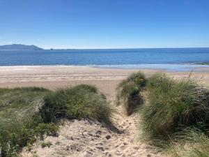 a sandy beach with some grass and the ocean at Shanadune in Tralee
