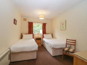 a room with two beds and a chair in it at Beech Timber Lodge in Keswick