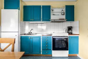 a kitchen with blue cabinets and a white refrigerator at Lovely holiday house by the lake Bolmen in Bolmsö