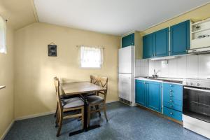 a kitchen with blue cabinets and a wooden table and chairs at Lovely holiday house by the lake Bolmen in Bolmsö