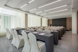 een conferentieruimte met tafels en stoelen en een scherm bij Lijiang Ancient City Kasion purey Hotel - Big waterwheel store in Lijiang +30 foto's