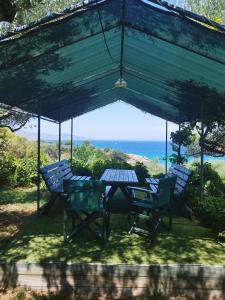 una mesa y sillas bajo un dosel con el océano en VILLA AGIA AIKATERINI en Amoudi