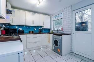 uma cozinha com armários brancos e uma máquina de lavar roupa em Anfield House em Liverpool