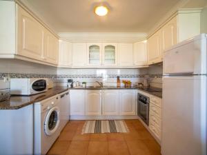 Una cocina con gabinetes blancos y lavadora y secadora. en Apartment Rota do Sol by Interhome, en Altura