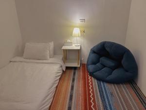 a bedroom with a bed and a blue chair at Back to spring BnB in Hengchun