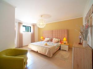 a bedroom with a pink bed and a chair at Apartment Bela Vista - PMO130 by Interhome in Lagoa