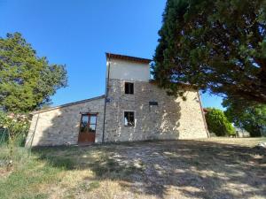 un antiguo edificio de piedra con un árbol en primer plano en Colle Costanza, en Todi