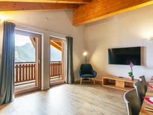 a living room with a television and a balcony at Apartment T-Resort La Tzoumaz 4p8 vue vallée by Interhome in La Tzoumaz