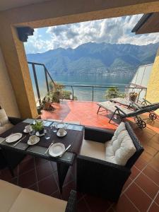 Pino Lago Maggiore的住宿－Lago Maggiore- Casa Roccia-Ferienwohnung in Pino sulla Sponda，阳台配有桌椅,享有水景。