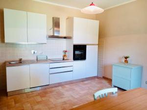 a kitchen with white cabinets and a wooden table at Colle Costanza in Todi
