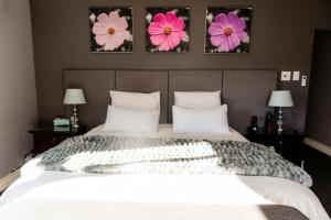 a bedroom with a large bed with three flowers on the wall at Valhalla, Cathkin Park in Bergview