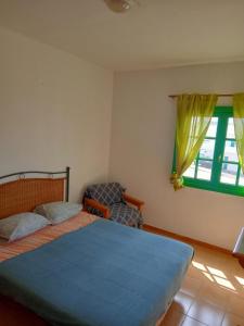a bedroom with a bed and a chair and a window at El Marinero, piso 2 y piso 3 in La Santa