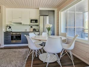 a kitchen with a table and white chairs in a room at Holiday Home Himoksen keiju 2 by Interhome in Jämsä