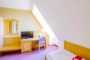 Schlafzimmer mit einem Schreibtisch, einem TV und einem Bett in der Unterkunft Hotel Schloss Nebra in Nebra