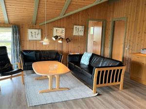 uma sala de estar com um sofá de couro preto e uma mesa em Holiday Home Juha - from the sea in Western Jutland by Interhome em Bjerregård