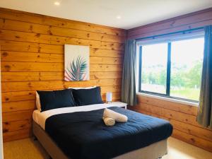 Enjoyable Cozy Life Style Villa في Dairy Flat: غرفة نوم بسرير مع جدار خشبي