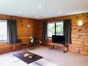 Enjoyable Cozy Life Style Villa في Dairy Flat: غرفة معيشة مع جدران خشبية وتلفزيون بشاشة مسطحة