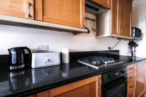 une cuisine avec des placards en bois et un comptoir noir dans l'établissement Harrods Knightsbridge Flat in Central KB89, à Londres